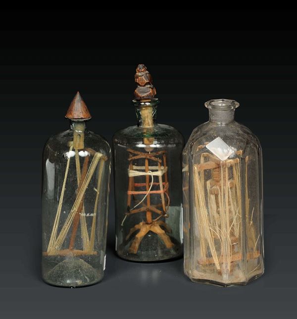 Tre piccole bottiglie in vetro soffiato e molato contenenti avvolgimatassa con filo, XIX secolo