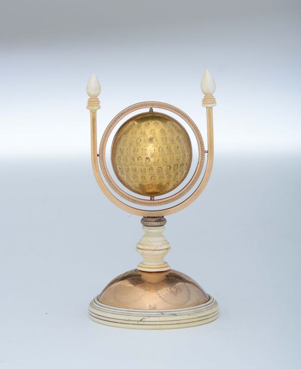 Raro oggetto in oro a forma di globo ruotabile su base circolare del medesimo materiale ed elementi in avorio tornito. Italia, Roma, seconda metà del XIX secolo