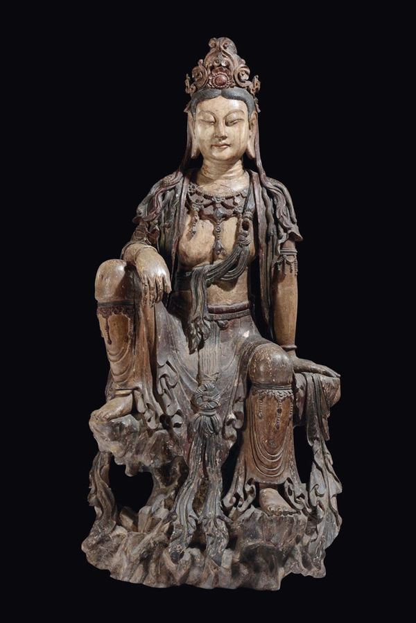 A large and important carved and polychrome wood figure of Guanyin seated on a rock, China, late Ming  [..]