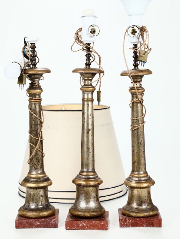 Tre candelieri in legno dorato su base in marmo rosso