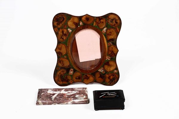 Lotto comprendente un scatolina portafiammiferi in legno ebanizzato con coperchio intarsiato in pietre dure, un presse papier in marmo rosa e una cornice in legno e pietre dure